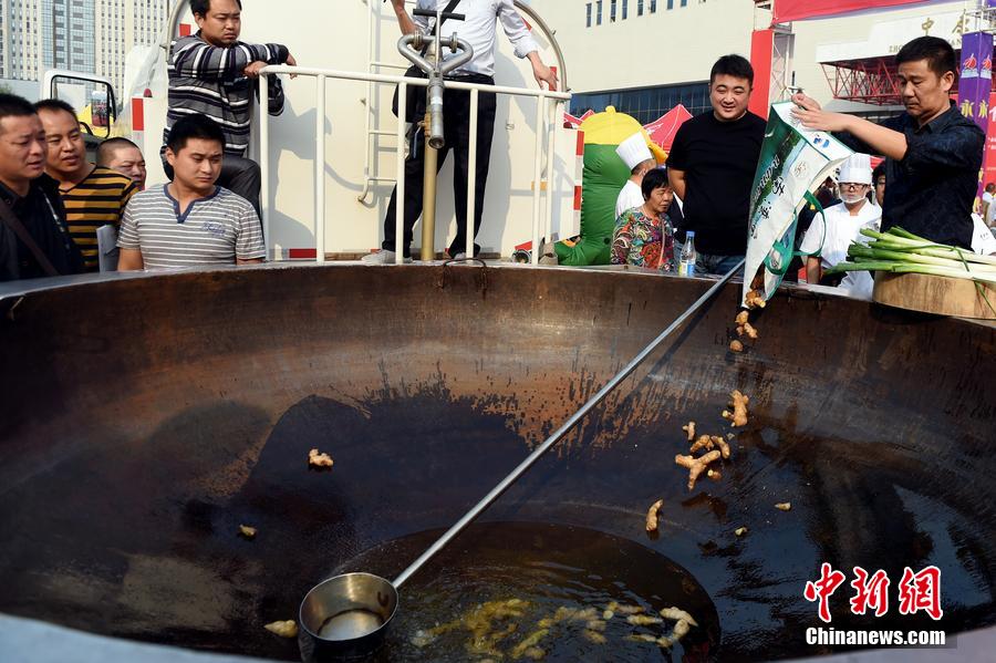 工作人員向大鍋內(nèi)加入油和姜等烹飪調(diào)料。 圖片來源：CFP視覺中國