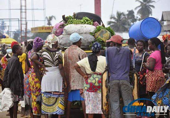 當(dāng)?shù)貢r(shí)間2014年8月14日，利比里亞蒙羅維亞，市場里的商人們圍著一輛汽車。