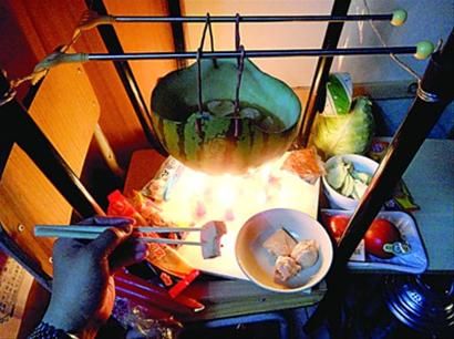 兩張椅子被面對面疊在一起，穿了兩根線的西瓜皮就懸空在椅腳中間，下面有蠟燭加熱，這就是西瓜火鍋。