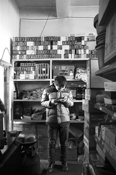 1月21日，周瑋在自家的超市里玩計(jì)算器。