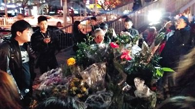 昨晚7時許，三里屯太古里西邊附近一過街天橋旁邊，聞訊而至的網友圍住了賣花老人，爭相買花。 網友“行者橙子”供圖