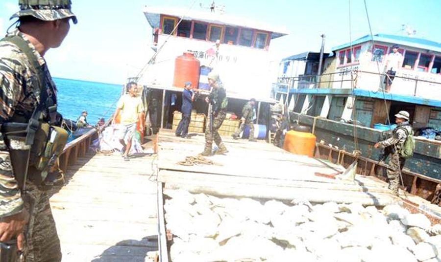 圖為菲律賓海軍持槍檢查中國(guó)漁民的照片。
