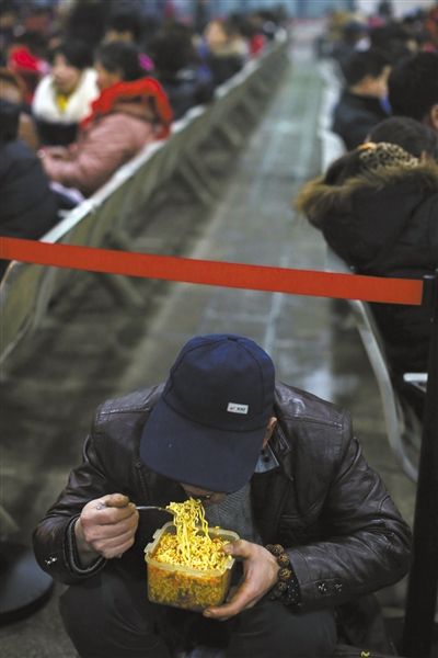 北京西站臨時候車廳，鄧軍吃著妻子泡好的方便面