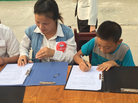 赤腳“小電工”張闖與結(jié)對(duì)幫扶的幸福使者代表在簽幫扶協(xié)議 攝影 張麗