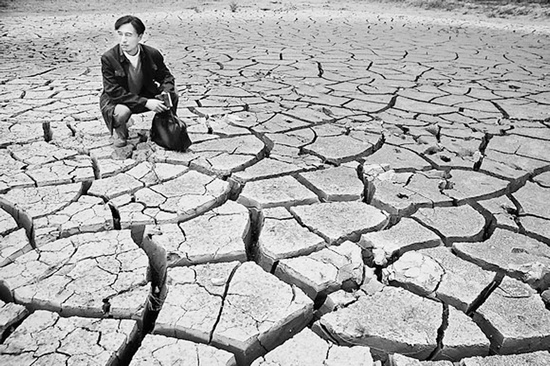蹲在干涸的田地里，焦裕祿為饑餓的百姓揪心不已 《焦裕祿》劇照